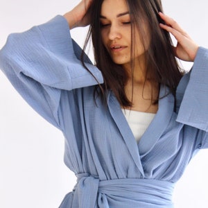 May include: A light blue wrap robe with a long tie belt. The robe is made of a soft, textured fabric.