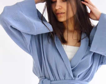 May include: A light blue wrap robe with a long tie belt. The robe is made of a soft, textured fabric.