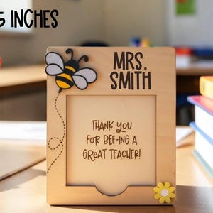 May include: A wooden notepad holder with a bee design, measuring 4 x 5 inches. The holder features the text "MRS. SMITH" and "THANK YOU FOR BEE-ING A GREAT TEACHER!" A yellow flower and a bee are also visible.