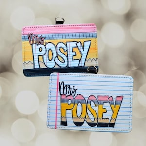 May include: Two rectangular luggage tags with the name "Mrs. Posey" in a colorful, cartoonish design. One tag has a pink top and a yellow and blue background, while the other has a white lined paper design. Each tag has a black loop.