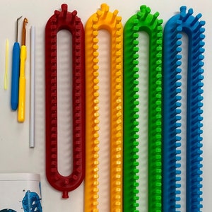 May include: A craft kit with four colorful knitting looms in red, yellow, green, and blue. The kit also includes crochet hooks, a yarn needle, and a white knitting tool. The looms are U-shaped with pegs for holding yarn, ideal for various knitting projects.