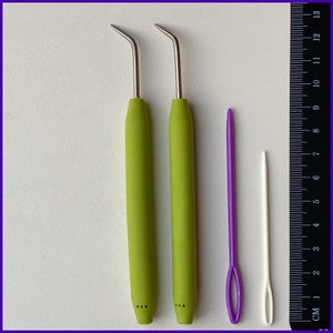 May include: Two green crochet hooks with metal tips and a purple and a white yarn needle. The needles are 13 cm long.