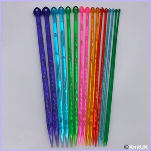 May include: A set of 16 colorful plastic knitting needles. The needles are arranged in a row from left to right, with the colors ranging from purple to green. The needles are all the same size and have a heart-shaped tip.