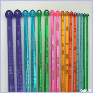 May include: A set of 16 colorful plastic knitting needles with a heart-shaped tip and a clear, textured finish. The needles are arranged in order of size, with the smallest needle on the left and the largest needle on the right.