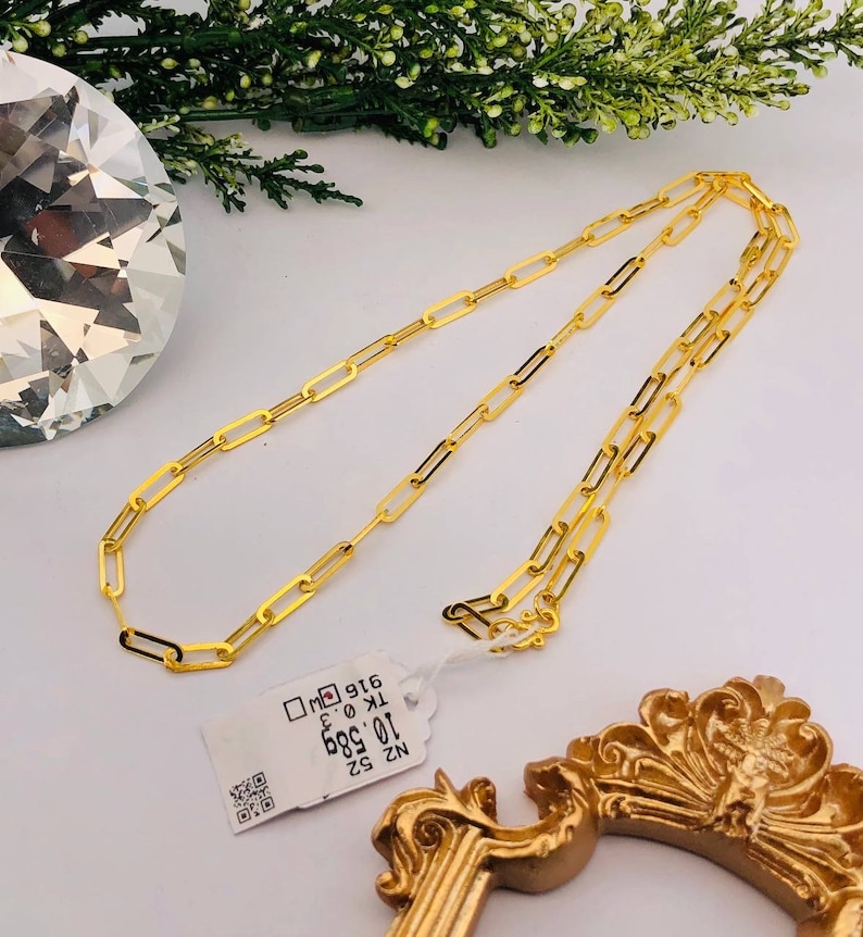 Puede incluir: Un collar de cadena de oro con una etiqueta de papel que dice "NZ 52 10.00g 886 K 18 916".