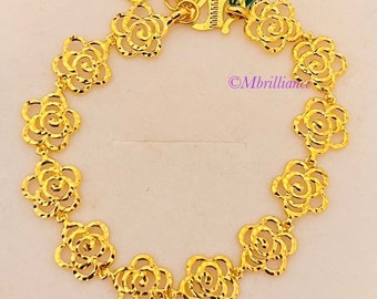 May include: A gold bracelet with a heart charm and a series of rose-shaped links. The bracelet is made of 24 karat gold and is a beautiful piece of jewelry.