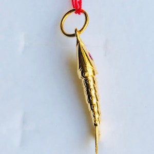 May include: A gold fish pendant with a red stone eye. The pendant is attached to a red string.