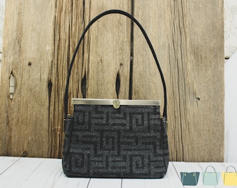May include: A small black and grey patterned handbag with a metal clasp and black handles.