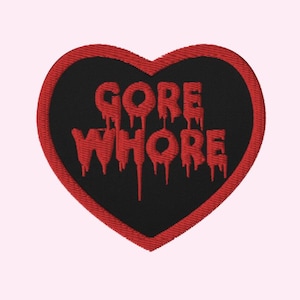 Peut inclure: Écusson brodé en forme de cœur. Le centre noir porte les mots "GORE WHORE" en lettres rouges dégoulinantes. Le cœur est souligné de rouge.