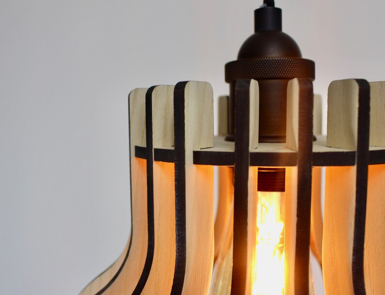 May include: A wooden pendant light with a geometric design. The light is made of thin strips of wood that are arranged in a grid pattern. The light is illuminated by a single light bulb.