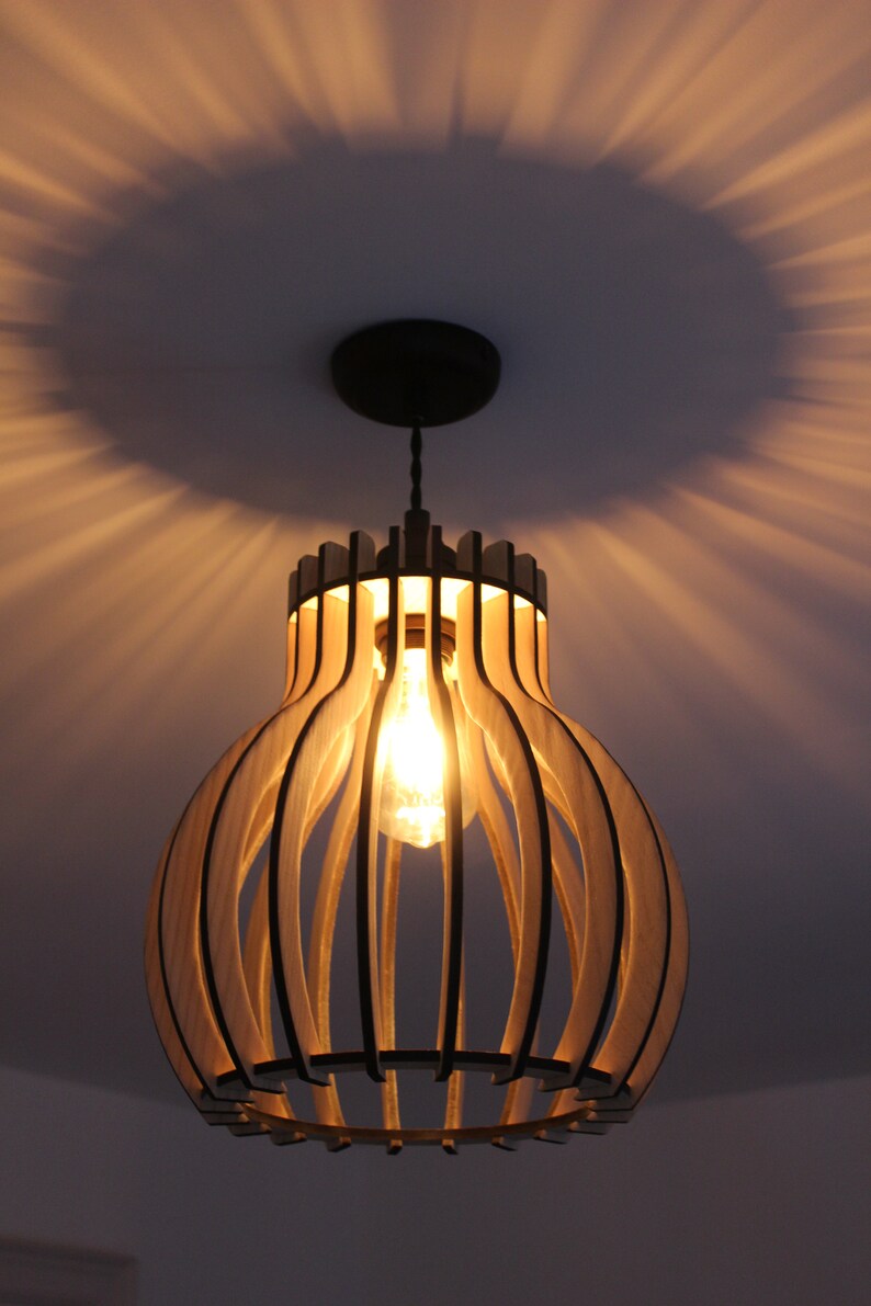 May include: A wooden pendant light fixture with a round, cage-like design. The light is on and illuminates the room with a warm glow.