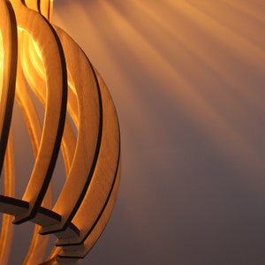 May include: A wooden light fixture with a warm, glowing light bulb. The fixture is made of thin, curved strips of wood that create a geometric pattern.