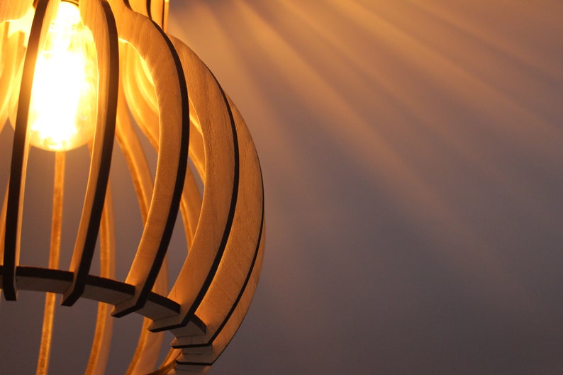 May include: A wooden light fixture with a warm, glowing light bulb. The fixture is made of thin, curved strips of wood that create a geometric pattern.