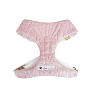 May include: A light pink dog harness with a quilted pattern. The harness has a white interior and straps, with a gold-colored clasp and the text "LOVE HACHI".