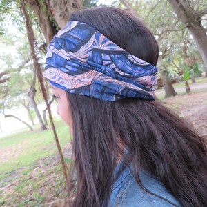 May include: A woman with long dark hair is wearing a blue and pink patterned headband. The headband is tied in a knot at the top of her head. She is wearing a blue denim jacket.