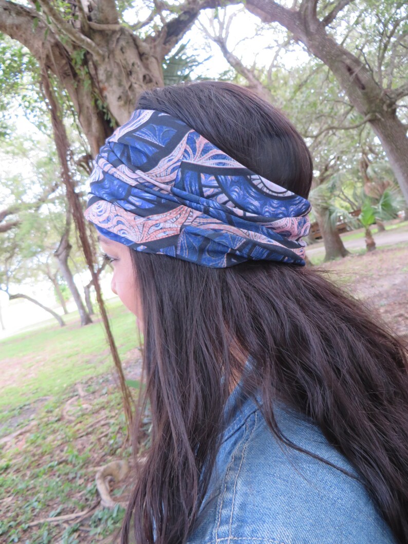 May include: A woman with long dark hair is wearing a blue and pink patterned headband. The headband is tied in a knot at the top of her head. She is wearing a blue denim jacket.