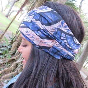 May include: A woman with long dark hair is wearing a blue and pink patterned headband. The headband is made of a soft, stretchy fabric and has a unique design.