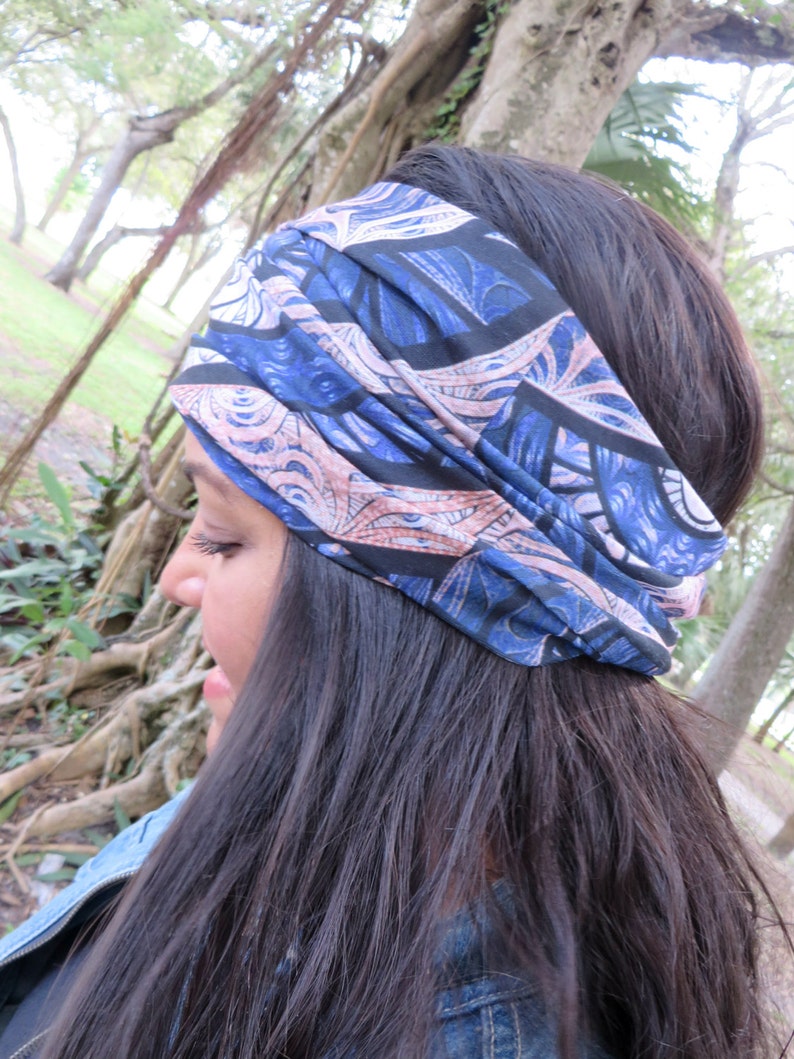 May include: A woman with long dark hair is wearing a blue and pink patterned headband. The headband is made of a soft, stretchy fabric and has a unique design.