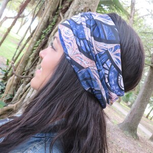 May include: A woman with long dark hair is wearing a blue and pink patterned headband. The headband is tied in a knot at the top of her head.