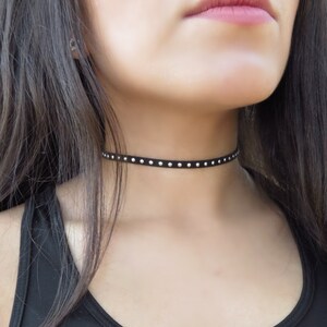 Puede incluir: Un collar gargantilla negro con tachuelas plateadas.