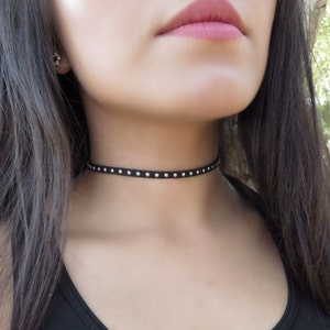 Puede incluir: Un collar gargantilla negro con tachuelas plateadas. La gargantilla est&aacute; hecha de un material fino y suave y es ajustable.