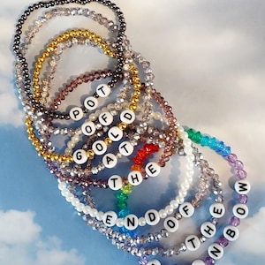May include: A set of eight beaded bracelets with different colored beads and letter charms spelling out the phrase "Pot of Gold at the End of the Rainbow".