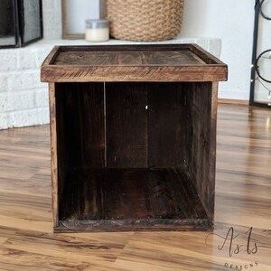 Peut inclure: Une bo&icirc;te de rangement en bois brun fonc&eacute; avec un couvercle. La bo&icirc;te est faite de bois de r&eacute;cup&eacute;ration et a un aspect rustique. La bo&icirc;te est vide et pr&ecirc;te &agrave; &ecirc;tre remplie d'objets.
