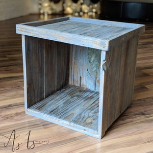 Peut inclure: Une bo&icirc;te carr&eacute;e en bois avec une finition peinture bleu clair. La bo&icirc;te a un couvercle et est faite de bois de r&eacute;cup&eacute;ration. La bo&icirc;te est pos&eacute;e sur un sol en bois.