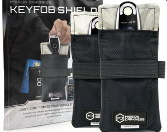 May include: Two black key fob signal blocking pouches with a white interior and a Mission Darkness logo. The pouches are designed to protect key fobs from being scanned by thieves.
