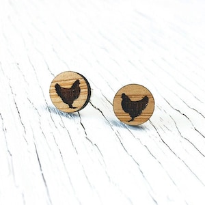Op de afbeelding: Een paar houten oorbellen met een silhouet van een kip op elke oorbel.
