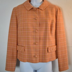 May include: A vintage orange plaid blazer with a classic collar and button-down front. The blazer features two front pockets and a tailored fit. The plaid pattern includes shades of orange, pink, and gold.