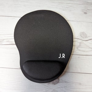 May include: Black mouse pad with a wrist rest and the initials "J.R." printed in white.