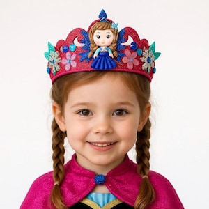 May include: A pink glitter crown with a doll figure and floral accents. The crown is worn by a young girl with braided hair, wearing a pink cape and dress.