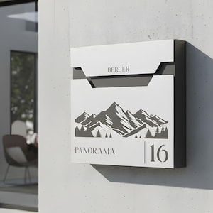 May include: A white mailbox with a mountain and tree graphic. The word "Panorama" and the number "16" are below the graphic. The word "BERGER" is above the graphic. The mailbox is mounted on a light gray wall.
