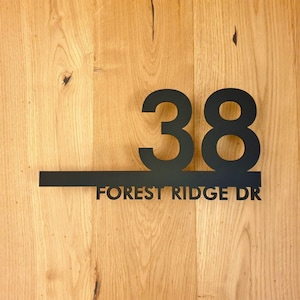 May include: Black metal house number plaque with the number 38 and the text "FOREST RIDGE DR" on a wooden background.