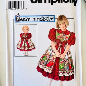 May include: A Simplicity sewing pattern envelope, number 7349, size BB 5,6,7,8, featuring a Daisy Kingdom design. The illustration shows a dress with red puff sleeves, a patterned skirt with holiday motifs, and a large red bow at the waist.