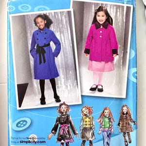 May include: A Simplicity 2534 sewing pattern envelope for children's coats, featuring two photographs of children wearing blue and magenta coats, along with four fashion illustrations of various coat styles and a barcode on a blue background.