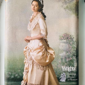 May include: A Simplicity sewing pattern envelope, number 244, featuring a photograph of a person wearing a champagne-colored gown with lace trim, a high collar, and a bustle. The text includes size RR 14, 16, 18, 20 and Wrights Victorian Bridal Museum.