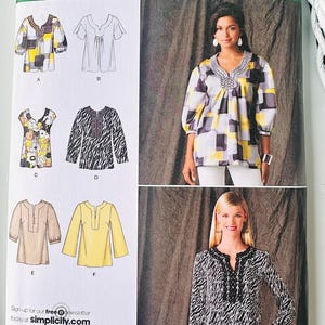 May include: A Simplicity 2696 sewing pattern envelope for six different tunic tops. The package displays illustrations of various necklines and sleeve lengths, along with photographs of two finished garments featuring geometric and animal print patterns.