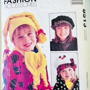 May include: A McCall's Fashion Accessories sewing pattern envelope 8513 featuring illustrations of three different hat styles. One hat is yellow with braided side pieces, one is a dark velvet beret, and one is a white snowman-themed hat.