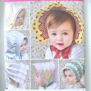 May include: A Simplicity 2908 sewing pattern envelope for infant bonnets in sizes XS, S, M, and L. The cover displays six variations of baby bonnets featuring different fabrics, lace trims, gingham patterns, and floral appliques with a red ribbon.