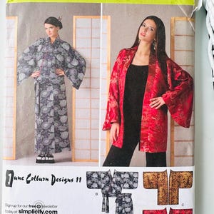 May include: A Simplicity sewing pattern envelope 2940 for robes and jackets. The front displays two garment styles: a long dark patterned robe and a shorter red patterned jacket. Text includes "Simplicity", "June Colburn Designs", and size range AA.