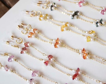 May include: A set of 12 gold chain eyeglass holders with different colored gemstone beads. Each holder has two chains and features a variety of colors, including pink, green, blue, and yellow.