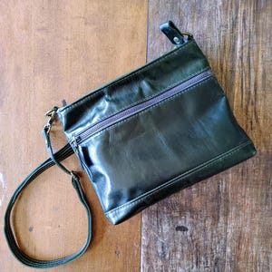 Cartera pequeña de piel italiana en color verde bosque oscuro con bolsillo con cremallera y correa cruzada. Tamaño perfecto para su billetera, teléfono móvil, llaves y pasaporte.