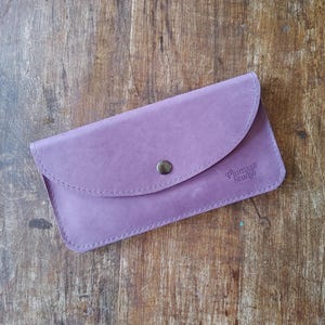 Pochette en cuir avec compartiments pour argent liquide et téléphone et trois emplacements pour cartes pouvant contenir plusieurs cartes. Fermeture à pression sur le rabat. Fabriqué au Canada