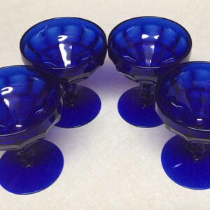 May include: Set of four cobalt blue glass dessert cups with a fluted design. The cups have a short stem and a round base.