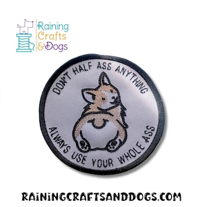 Könnte beinhalten: Ein runder Aufnäher mit einer Corgi-Illustration und dem Text "DON'T HALF ASS ANYTHING ALWAYS USE YOUR WHOLE ASS". Der Aufnäher hat einen schwarzen Rand und einen hellgrauen Hintergrund. Der Corgi ist von hinten abgebildet.