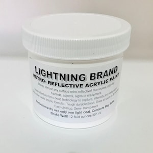 May include: A white plastic jar of Lightning Brand Retro-Reflective Acrylic Paint. The label includes product details and instructions. The jar contains 12 fluid ounces, or 355 ml, of paint.