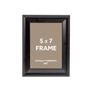 May include: A black rectangular 5 x 7 inch frame with a brown interior. The text "5 x 7 FRAME" is centered in white, with "TOTALLY TORONTO ART" below. The frame has a glossy finish.