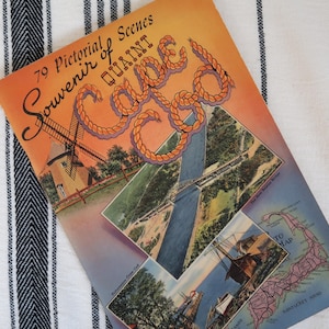 May include: Vintage souvenir booklet titled "79 Pictorial Scenes of Quaint Cape Cod." The cover features a windmill illustration, rope-style lettering, and several inset images of Cape Cod landmarks. The booklet is set against a striped background.